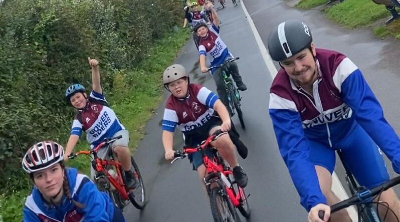 A picture of adults and young people riding bikes in Gower Riders shirts